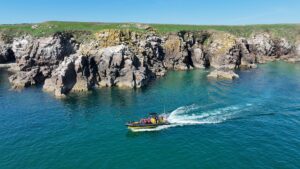 image of a speed boat on blue water passing by the cliffs of the saltee islands in wexford