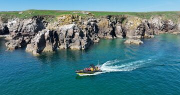 image of a speed boat on blue water passing by the cliffs of the saltee islands in wexford